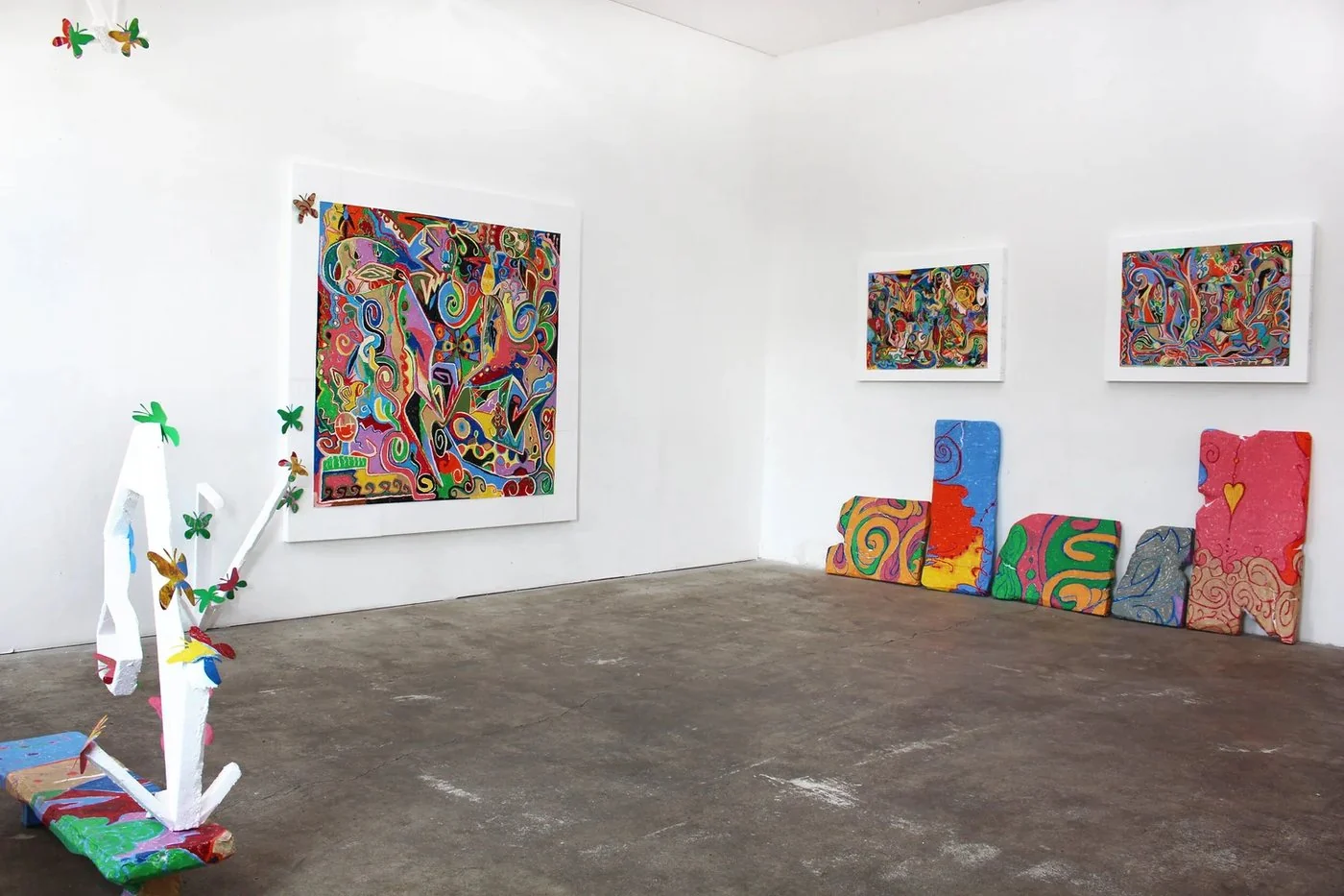 Målningar, målade objekt och en fristående skulptur i ett galleri