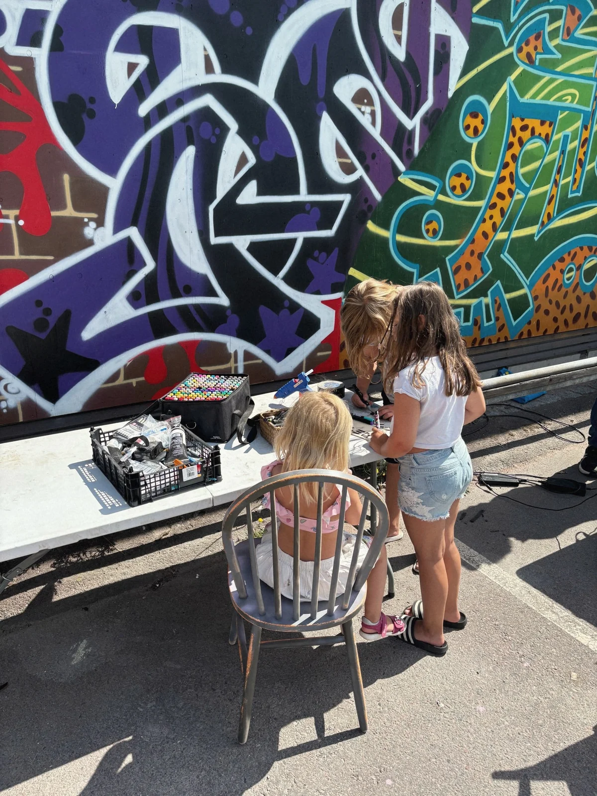 Barn vid ett tecknarbord framför graffitimuralen, sedda bakifrån