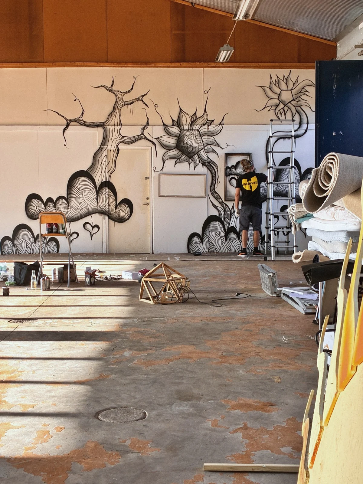 Muralmåleri med träd och figurer på en vägg i en stor lokal